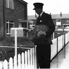 A postman delivering mail to a garden gate letter box in Bedwell Plash. | Stevenage Museum